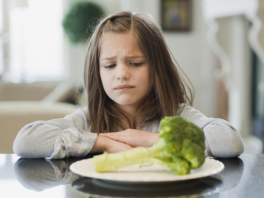 USA,Utah,Alpine,Girl (8-9) unfriendly looking at broccoli Photograph by RubberBall Productions
