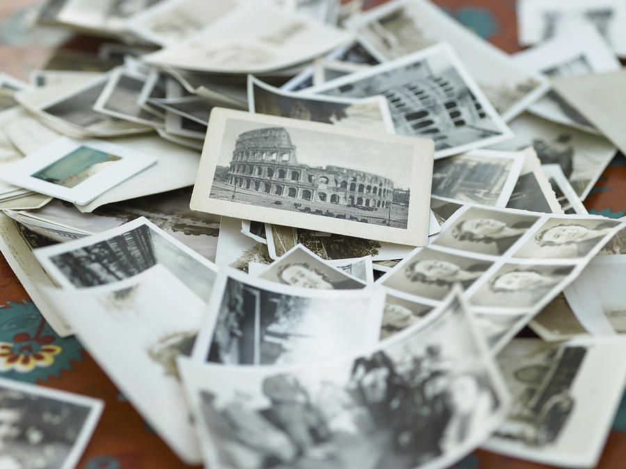 Various black and white photographs in pile on table Photograph by Michael Blann