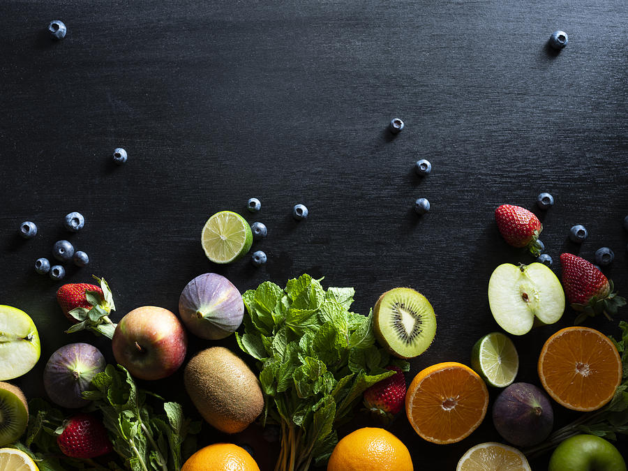 Various Cut And Whole Fruit On Dark Background. Photograph by Jenner Images