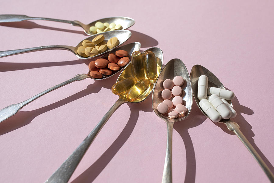 Various of spoons with pills and tablets on the pink background Photograph by Yulia Reznikov