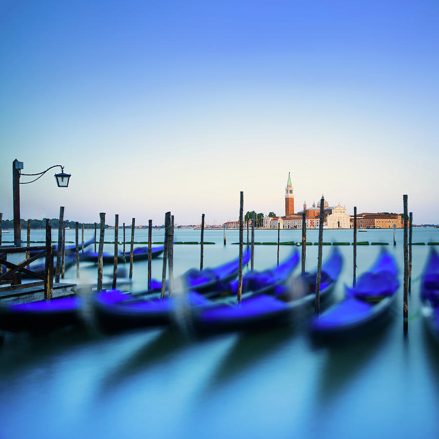 Venice, gondolas or gondole on sunset and church on background.  Photograph by Stefano Orazzini