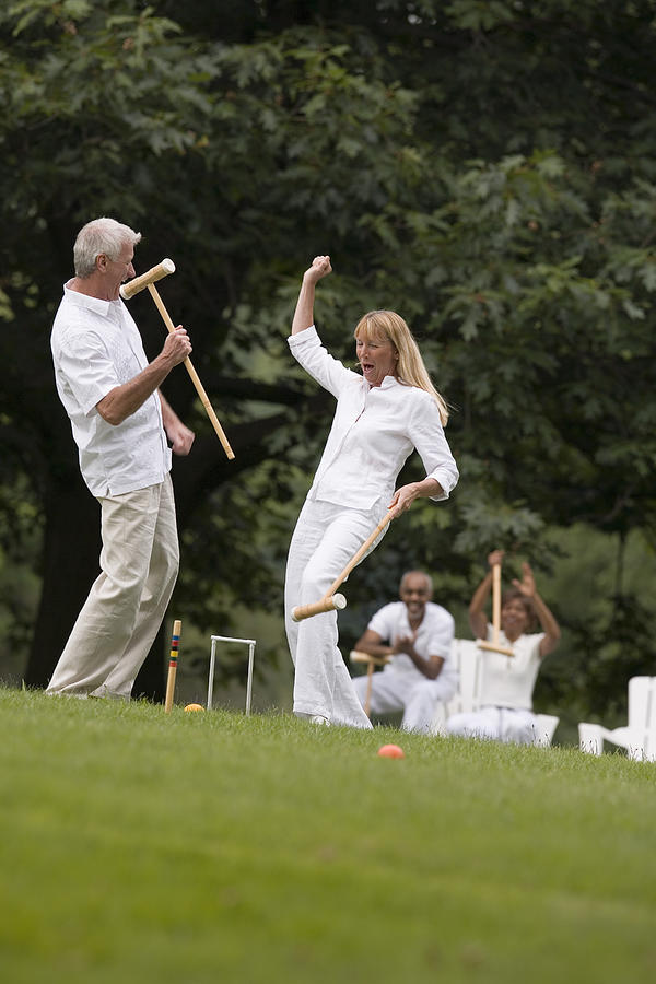 Victorious couple playing croquet Photograph by Comstock Images