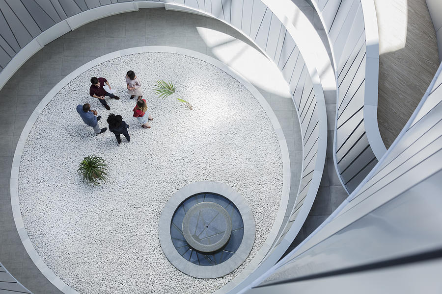 View from above business people talking in round modern office atrium courtyard Photograph by Caia Image