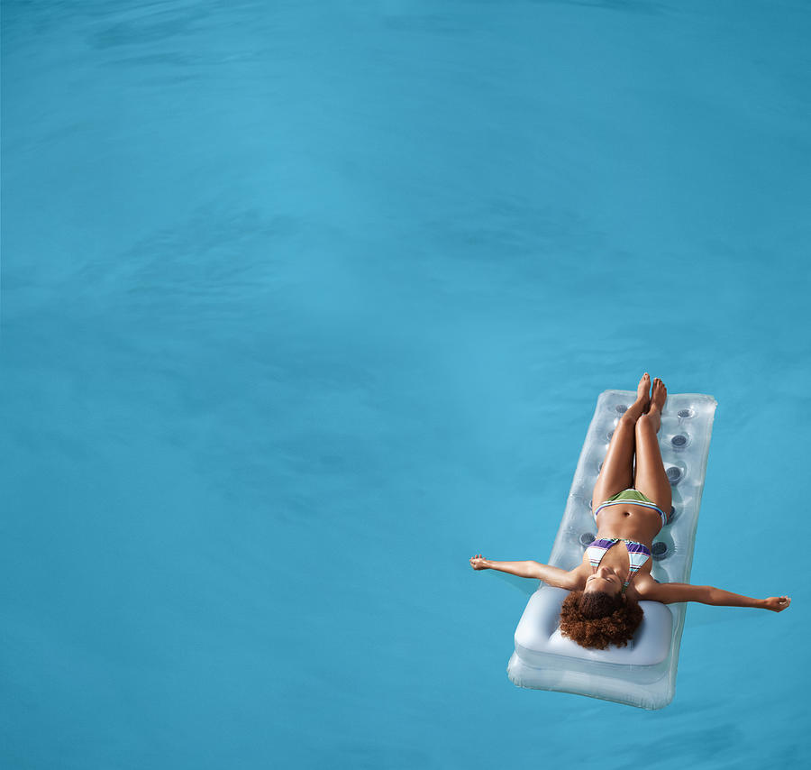 View of a female floating in swimming pool Photograph by Goodboy Picture Company