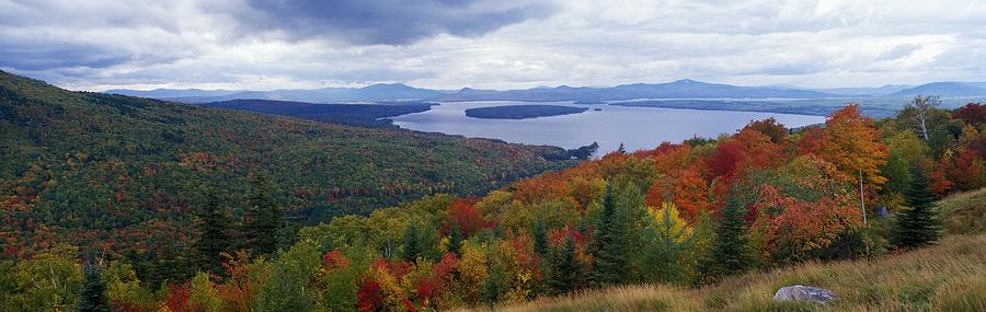 View of colorful fall foliage and approaching storm clouds from scenic overlook called Height of Land. Height of Land, Mooselookmeguntic Lake, Maine, North America. Photograph by Jeff Foott