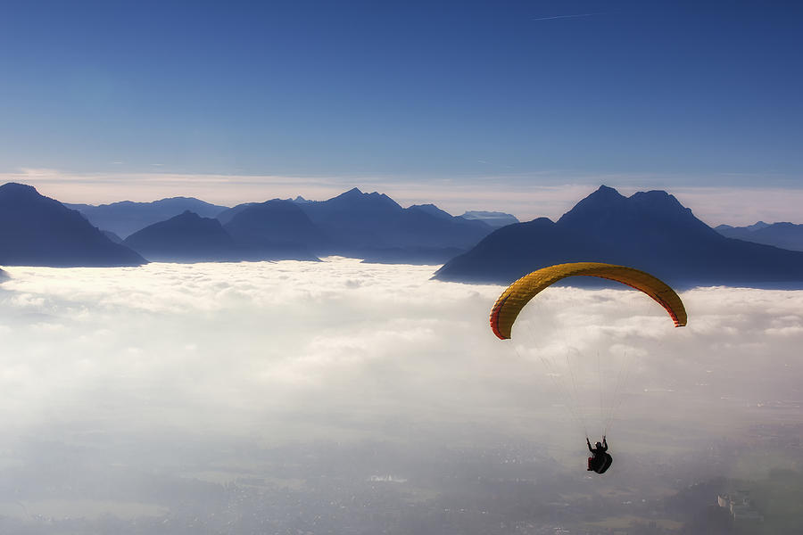 View of man skydiving from above the clouds with mountains Photograph by DieterMeyrl
