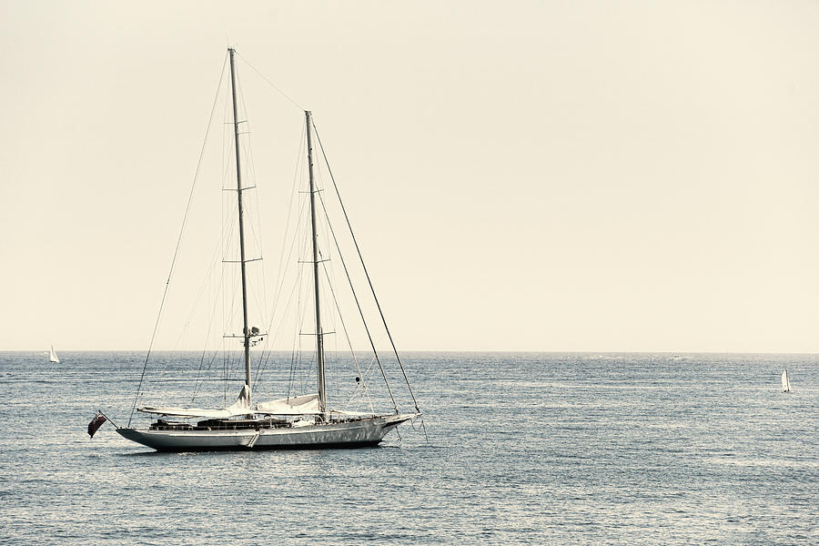 Vintage two-masted sailboat anchored close to the coast on the F Photograph by Jean-Luc Farges