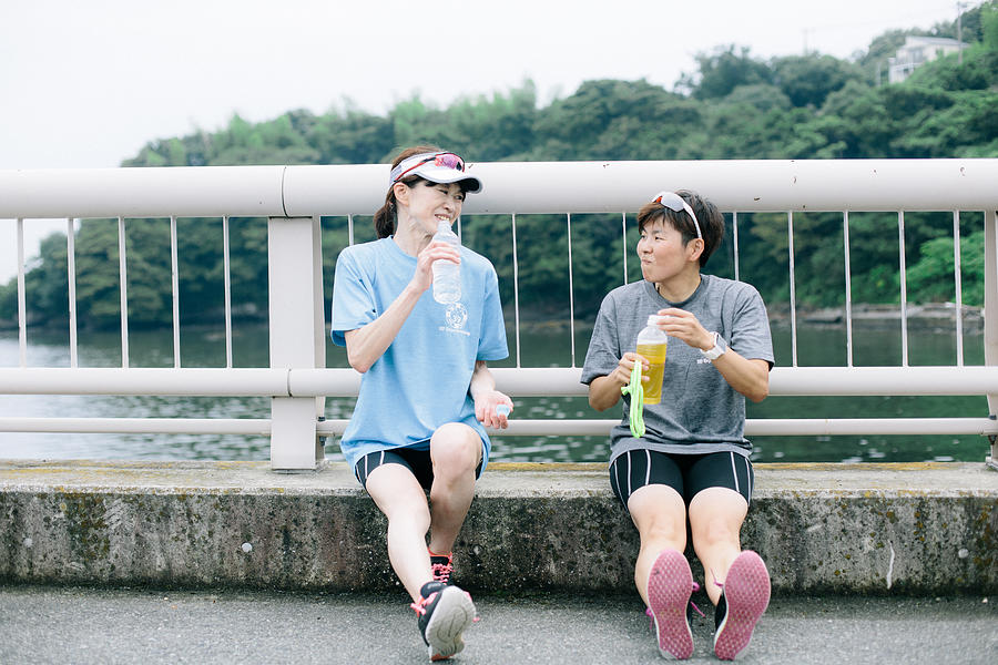 Visually impaired female triathlete taking a break from training together with her guide and coach Photograph by Eri Miura
