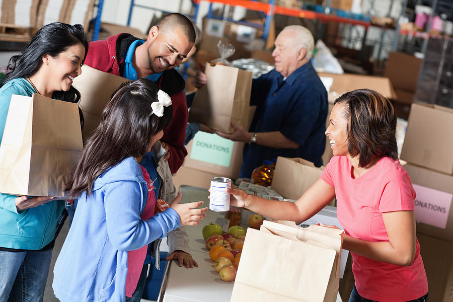 Volunteer accepting donations from family at food bank Photograph by SDI Productions