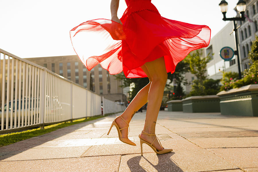 Waist down view of young woman twirling whilst wearing red dress Photograph by Zave Smith