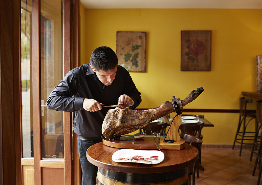 Waiter cutting serrano ham by hand Photograph by Klaus Vedfelt