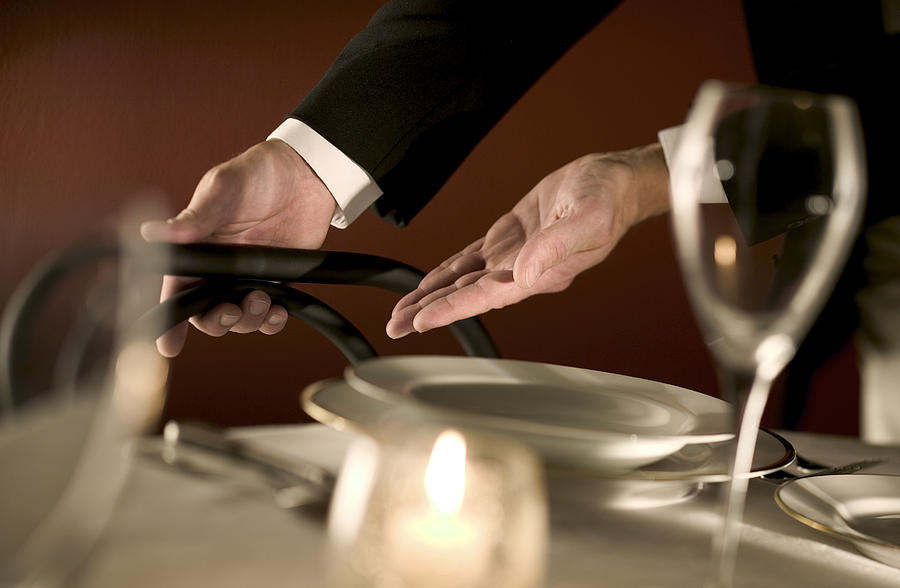 Waiter indicating a seat Photograph by Comstock Images