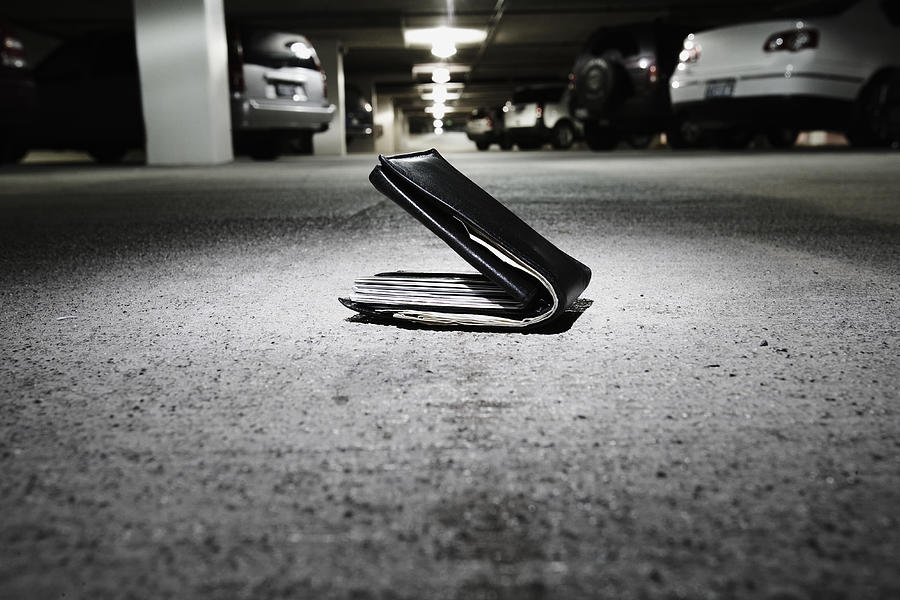 Wallet on concrete in parking garage (focus on wallet) Photograph by Thomas Northcut