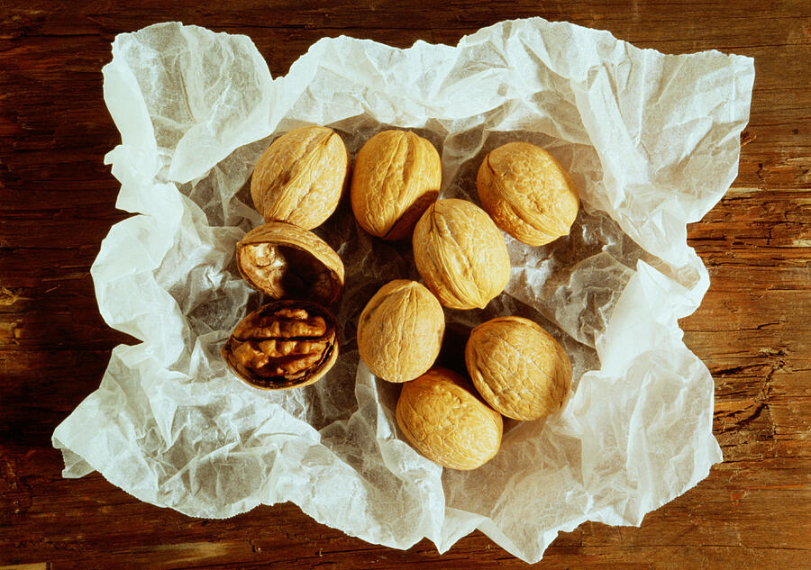 Walnuts On White Crumpled Paper Photograph by Nino Mascardi