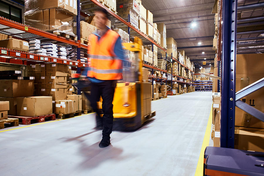 Warehouse, worker with a forklift in motion blur. Photograph by Tempura