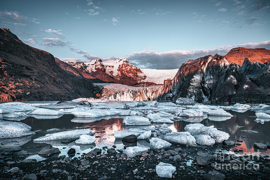Warm sunlight across the ice and mountains of Svinafellsjokul glacier at sunset, southern iceland. Part of the larger Vatnajokull glacier, the largest ice cap in iceland. Dark and moody style. Photograph by Jane Rix