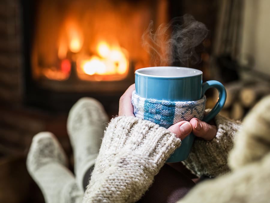 Warming and relaxing near fireplace with a cup of hot drink. Photograph by ValentynVolkov
