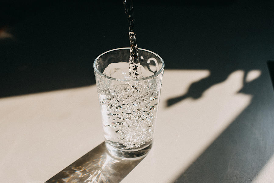 Water being poured in a glass of water that cast a beautiful shadow on a white kitchen countertop Photograph by Stefania Pelfini, La Waziya Photography