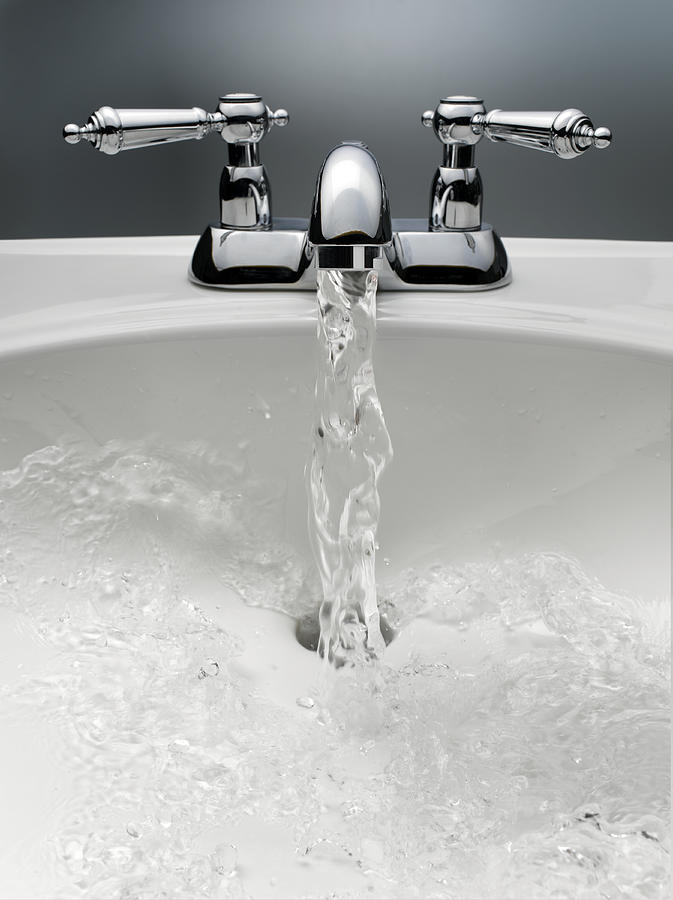 Water pouring from sink faucet Photograph by Jeffrey Hamilton