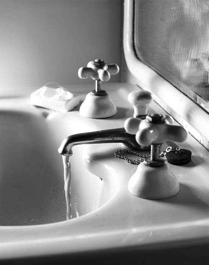 Water running from bathroom sink faucet (B&W) Photograph by Paul Avis