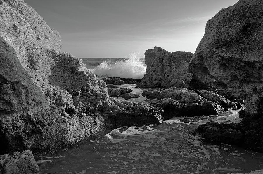 Black And White Photograph - Wave Crushing Rocks in Gale Beach - Monochrome by Angelo DeVal