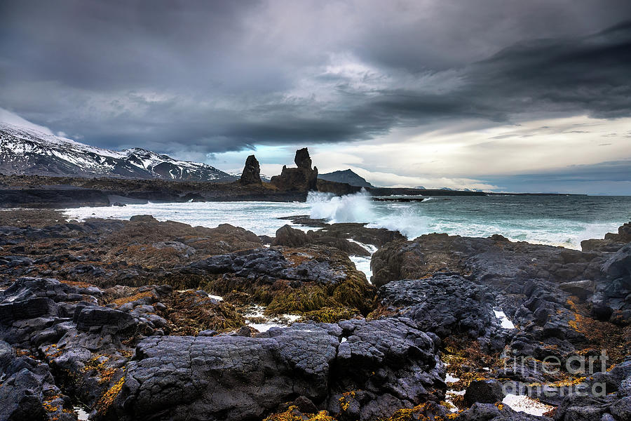 Waves crash onto the shoreline in front of Longdrangar, a pair of basalt rock outcrops on the Snaefellsnes Peninsula, Iceland. Photograph by Jane Rix