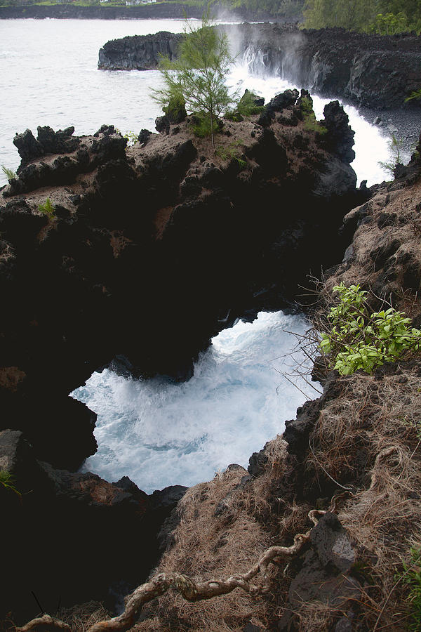 Waves splash under a natural bridge of lava rock Photograph by Timothy Hearsum