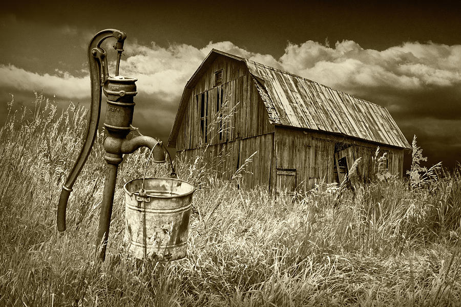 Weathered Wooden Barn with Water Pump and Metal Bucket in Sepia Tone Photograph by Randall Nyhof