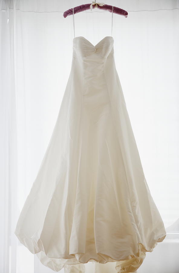 Wedding dress on hanger, studio shot Photograph by Jamie Grill