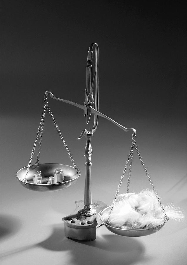 Weighing scales with feathers and weights, b&w. Photograph by Laurent Hamels