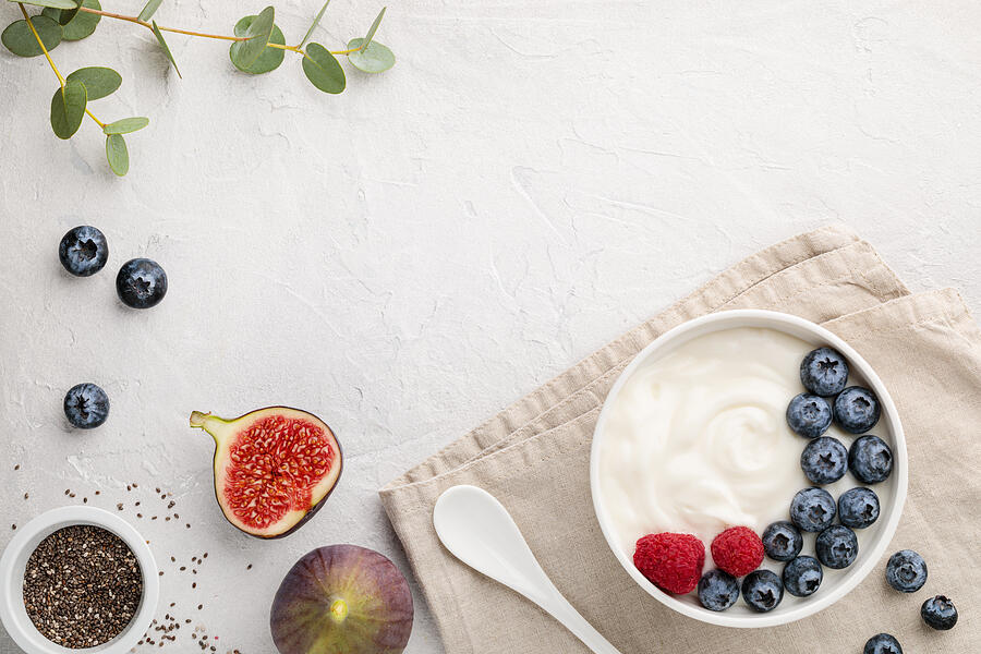 White fermented yogurt with blueberry, figs, chia seeds and raspberry in bowl on light gray table Photograph by Olga Buntovskih