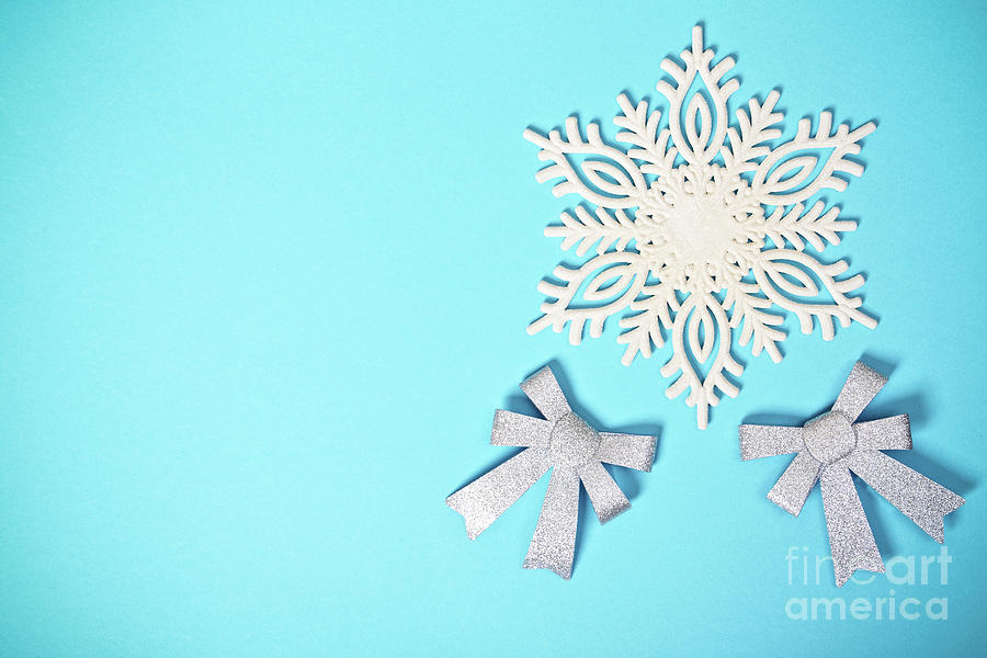 White glittery snowflake and bows on pastel blue background Photograph by Mendelex Photography