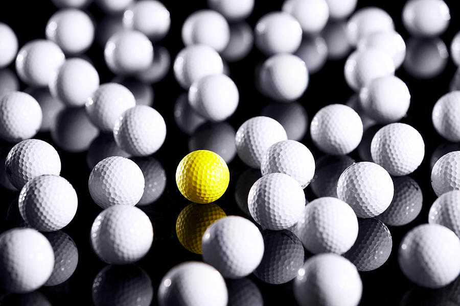 White golf balls with one yellow one Photograph by Thomas Northcut