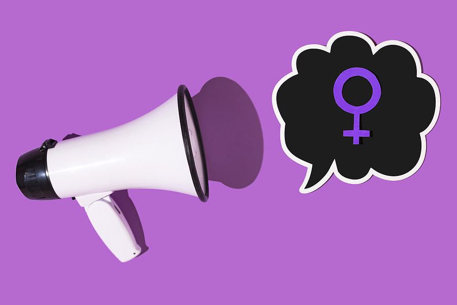 White megaphone with comic speech bubble with the symbol of the woman in purple, on purple background. Concept of womens day, empowerment, equality, inequality, activism and protest. Photograph by DBenitostock