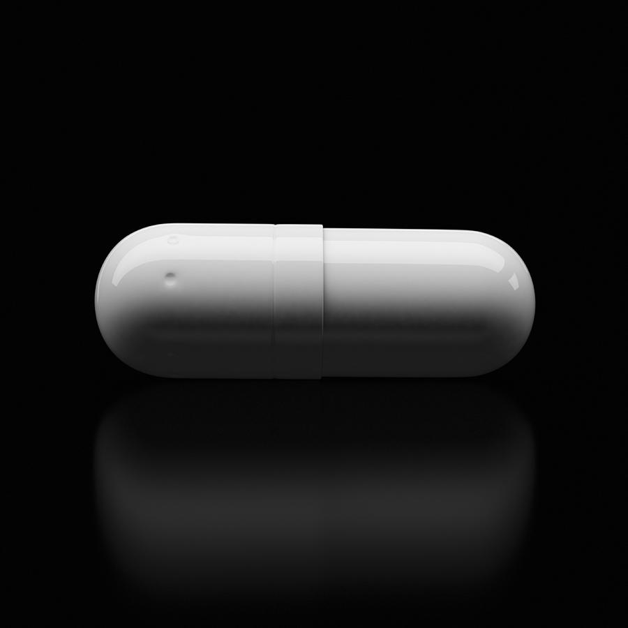 White pill resting on a reflective black surface Photograph by I Like That One