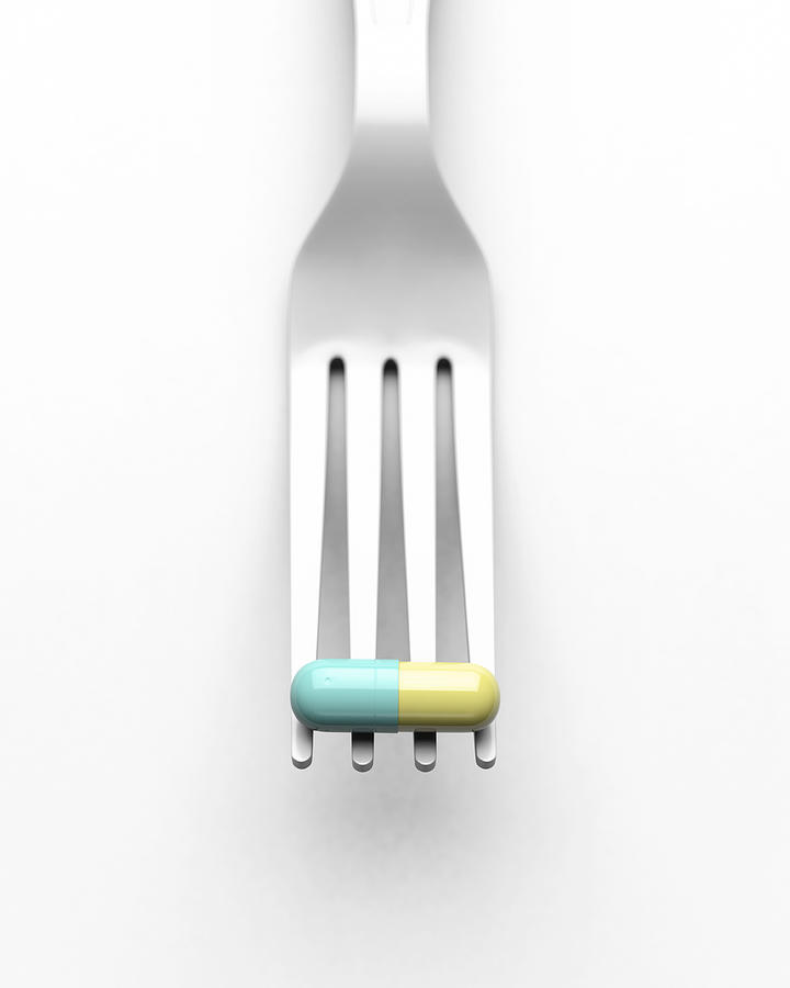 White plastic fork holding a green and yellow pill Photograph by I Like That One