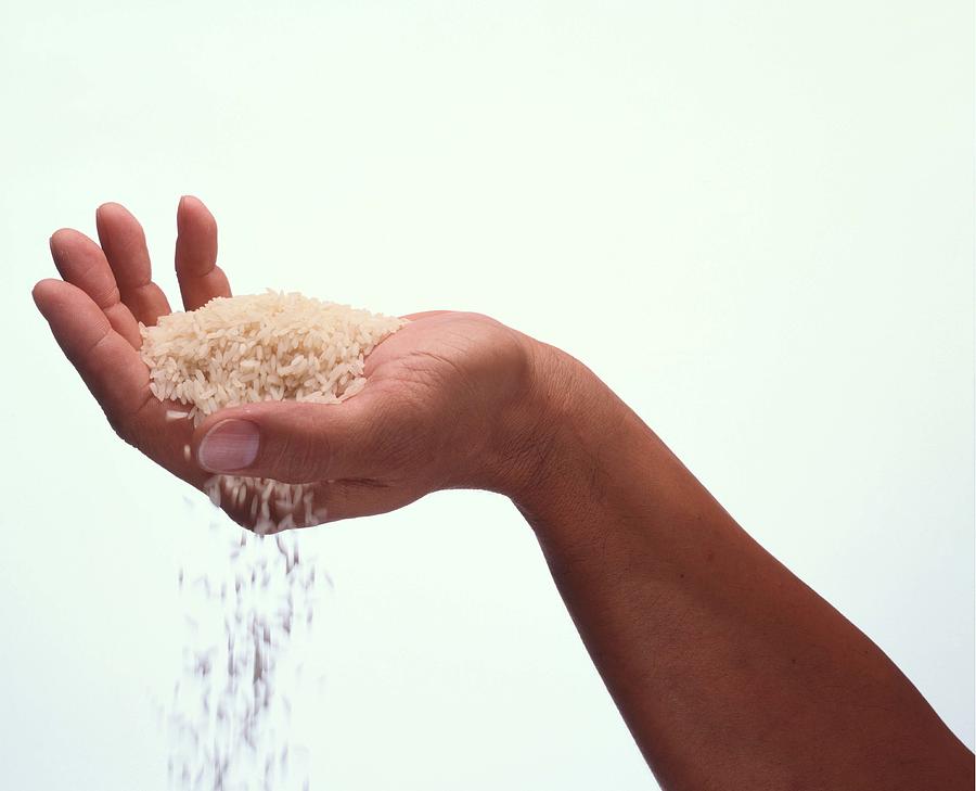 White rice falling from hand Photograph by Jupiterimages