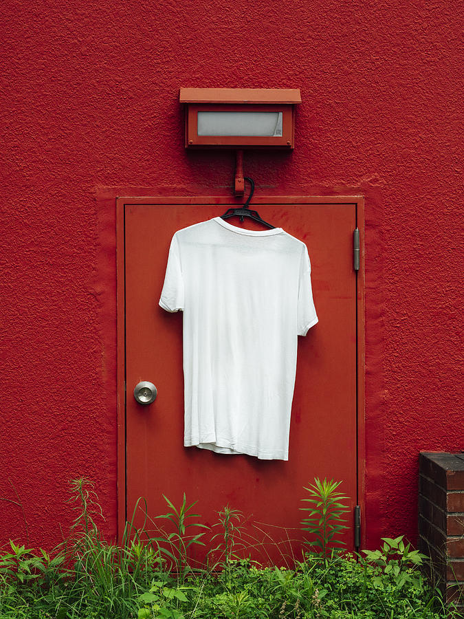 White T-shirt hangs on the red wall Photograph by EujarimPhotography