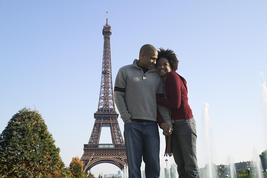 Wide Shot Of A Young Adult Couple As They Cuddle Together At The Eiffel Tower In Paris Photograph by Photodisc