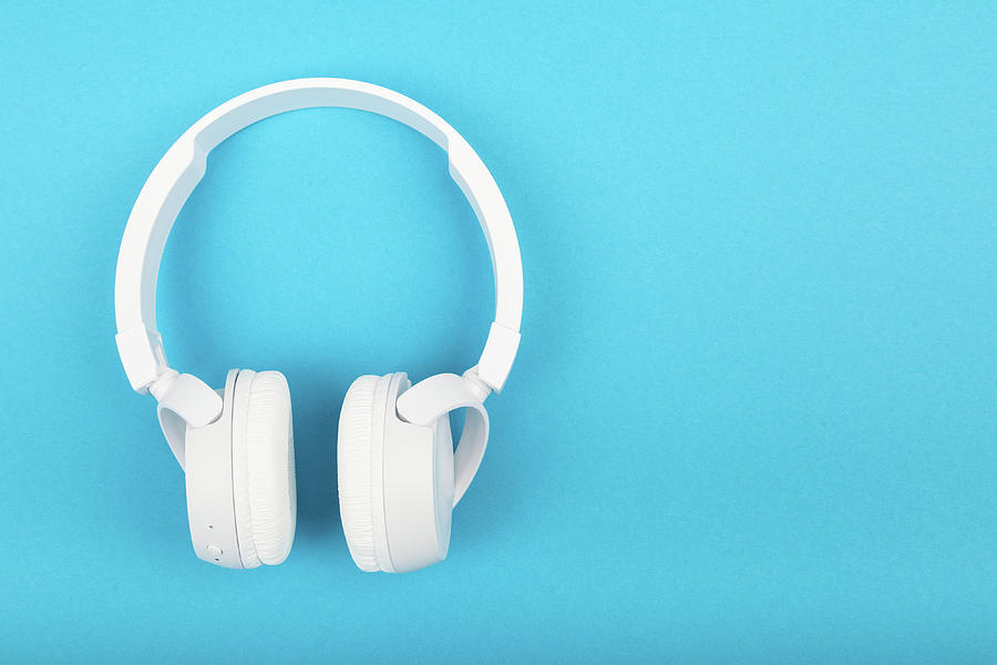 Wireless White Headphones On Blue Background. Music Concept. Earphones On Blue Background. Photograph