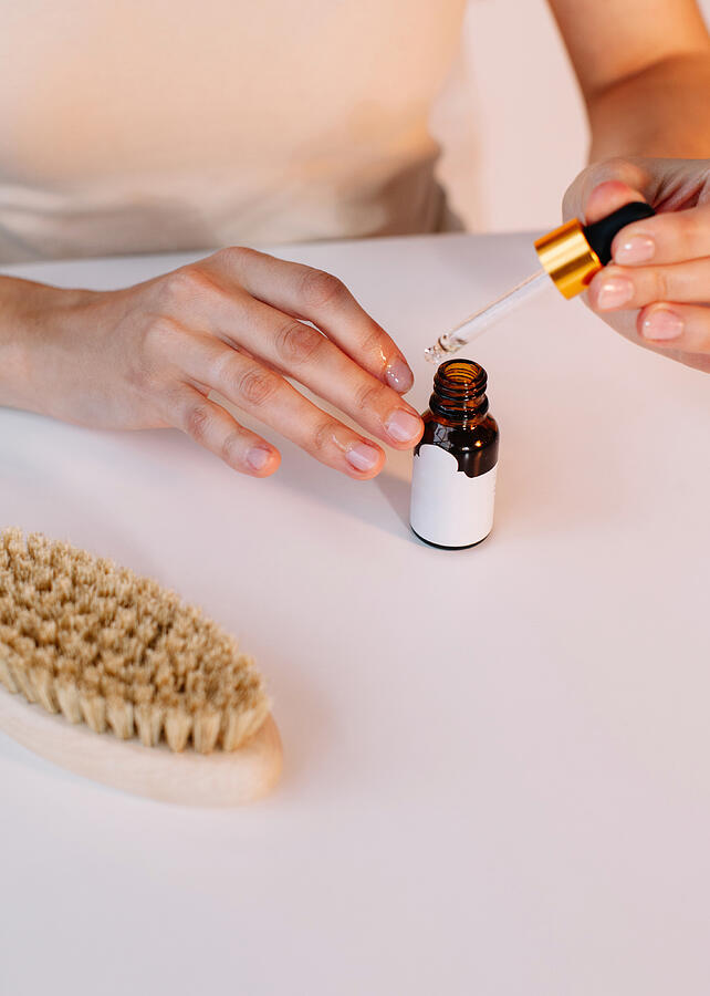 Woman applying cuticle oil to her nails Photograph by Honey_and_milk