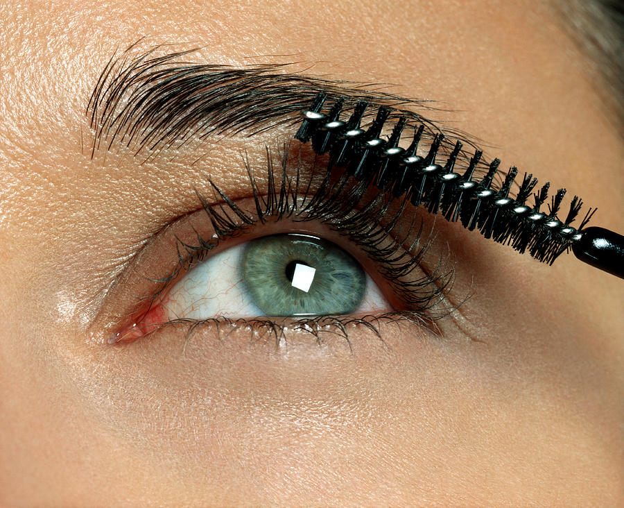 Woman applying eyelash makeup, close-up Photograph by Andreas Kuehn