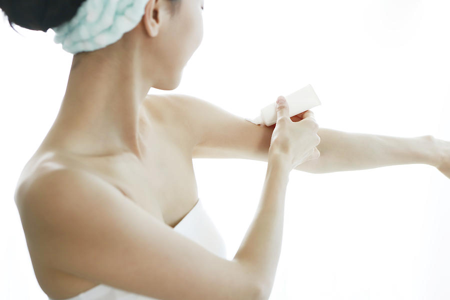 Woman applying moisturizer on arm Photograph by Runstudio