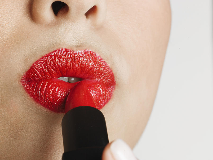 Woman applying red lipstick, puckering, close-up of mouth Photograph by Christopher Robbins