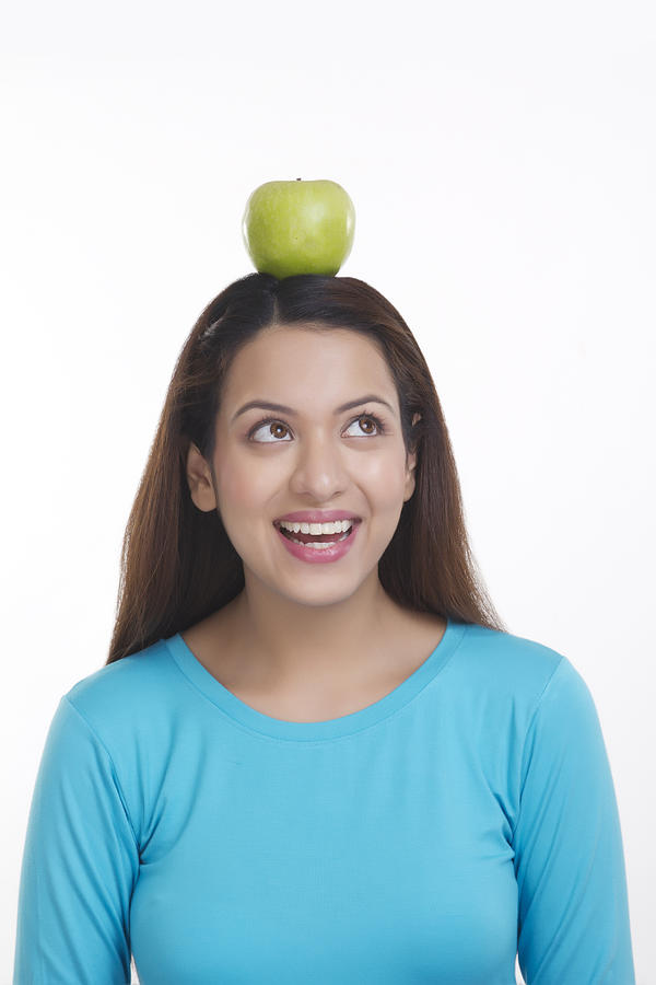 Woman balancing apple on head Photograph by IndiaPix/IndiaPicture