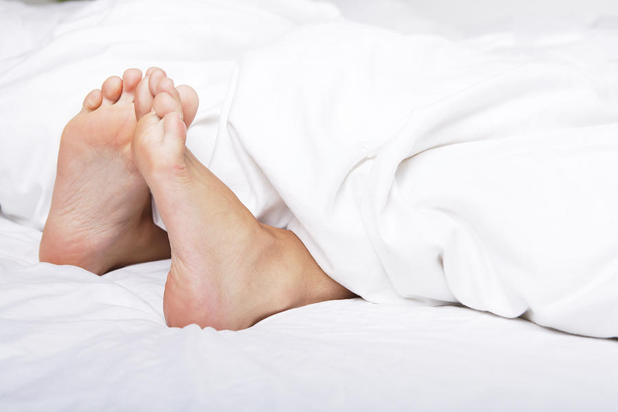Woman bare feet under blanket Photograph by ChristopherBernard