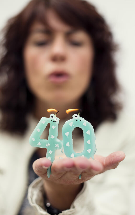 Woman blowing out candles for 40th birthday Photograph by Elenaval