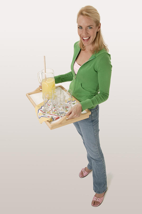 Woman carrying tray with lemonade Photograph by Comstock Images