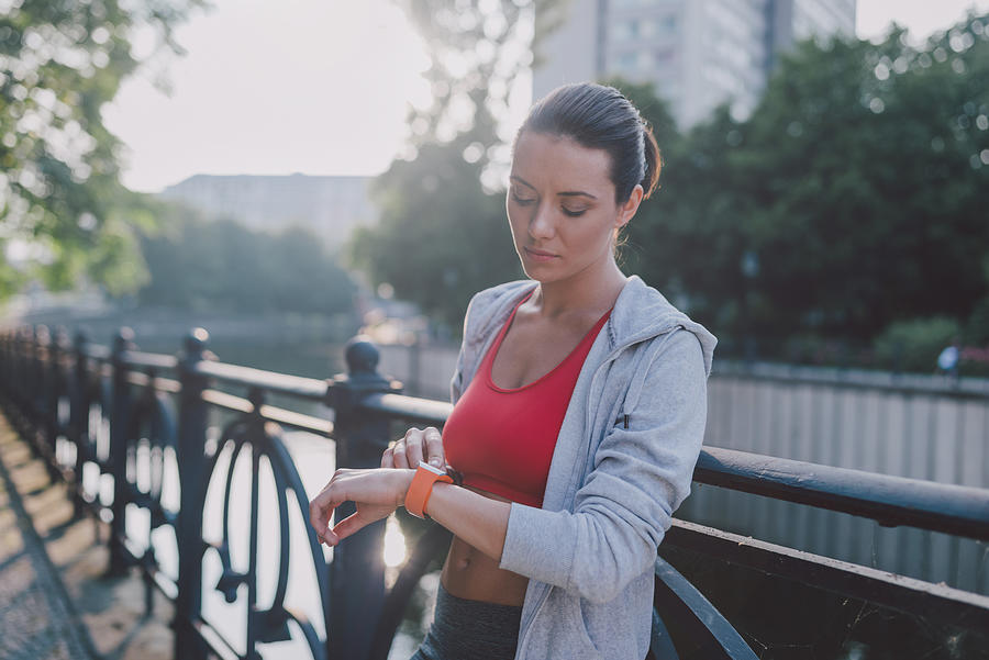 Woman checking smartwatch after sport. Photograph by Guido Mieth