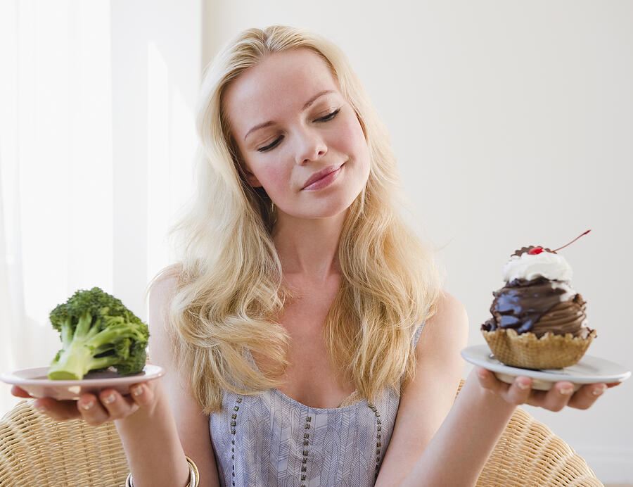 Woman choosing between broccoli or sundae Photograph by Jamie Grill
